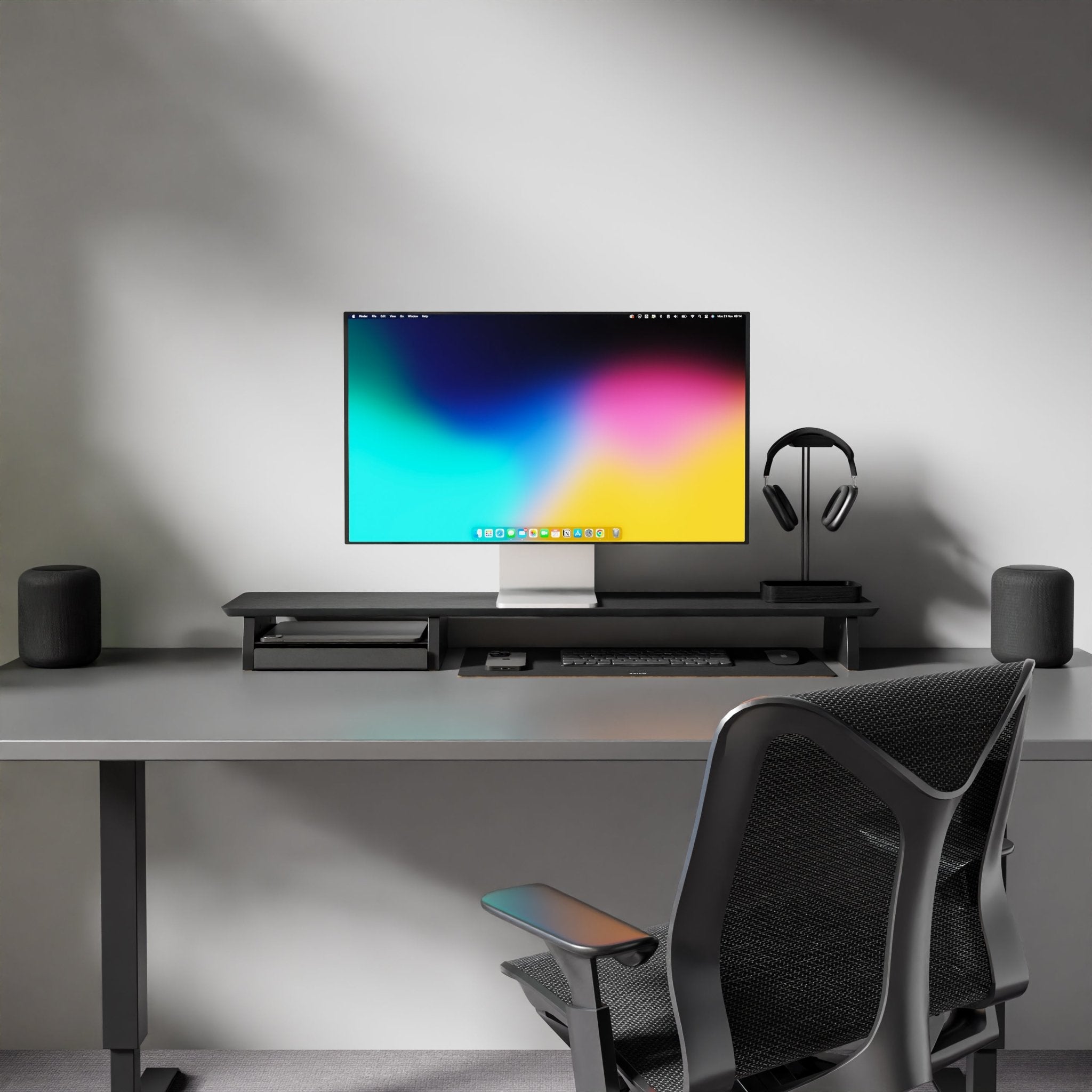 a desk setup with a sleek black Raico Desk Shelf for monitor stand. Made from 15-ply Premium Walnut Hardwood, this shelf is functional, and its black color adds a touch of sophistication to the desk. a black leather desk mat, adding a touch of luxury